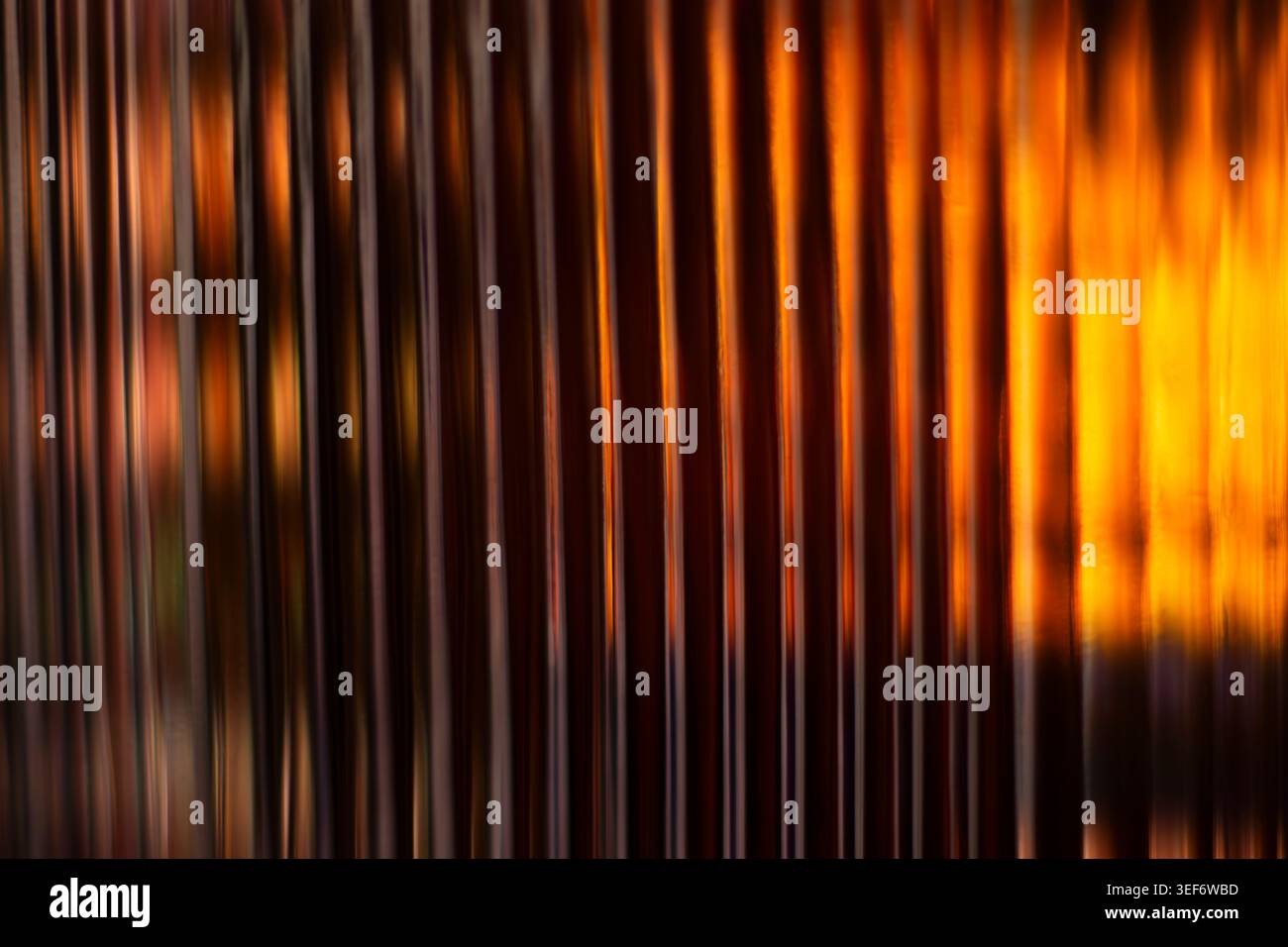 Golden amber glowing light lines passing through corrugated glass pattern Stock Photo