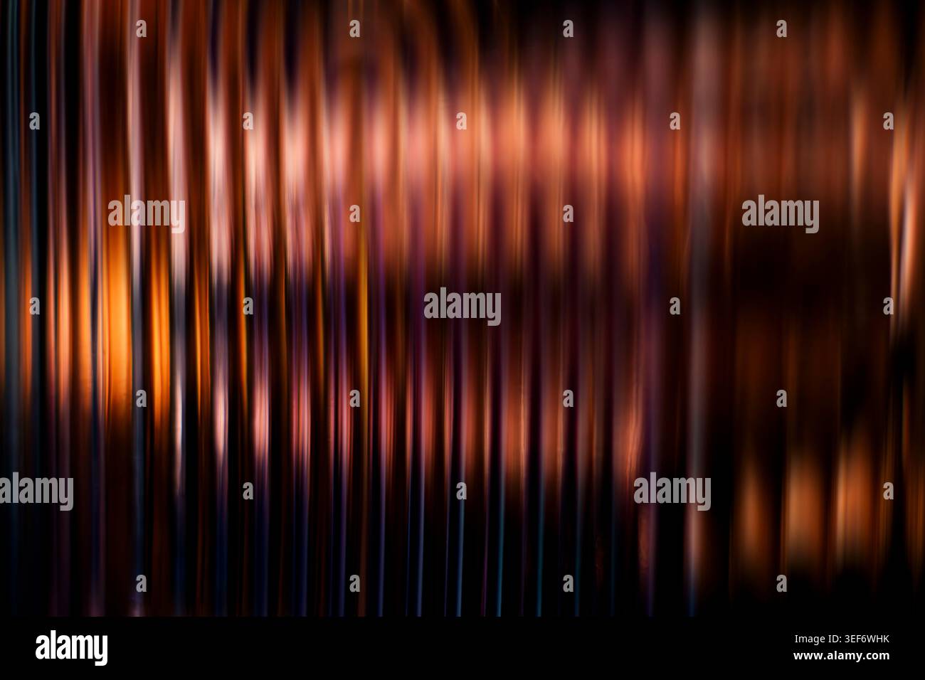Dark copper and orange abstract vertical blurred lines creating a warm metallic ribbed texture Stock Photo