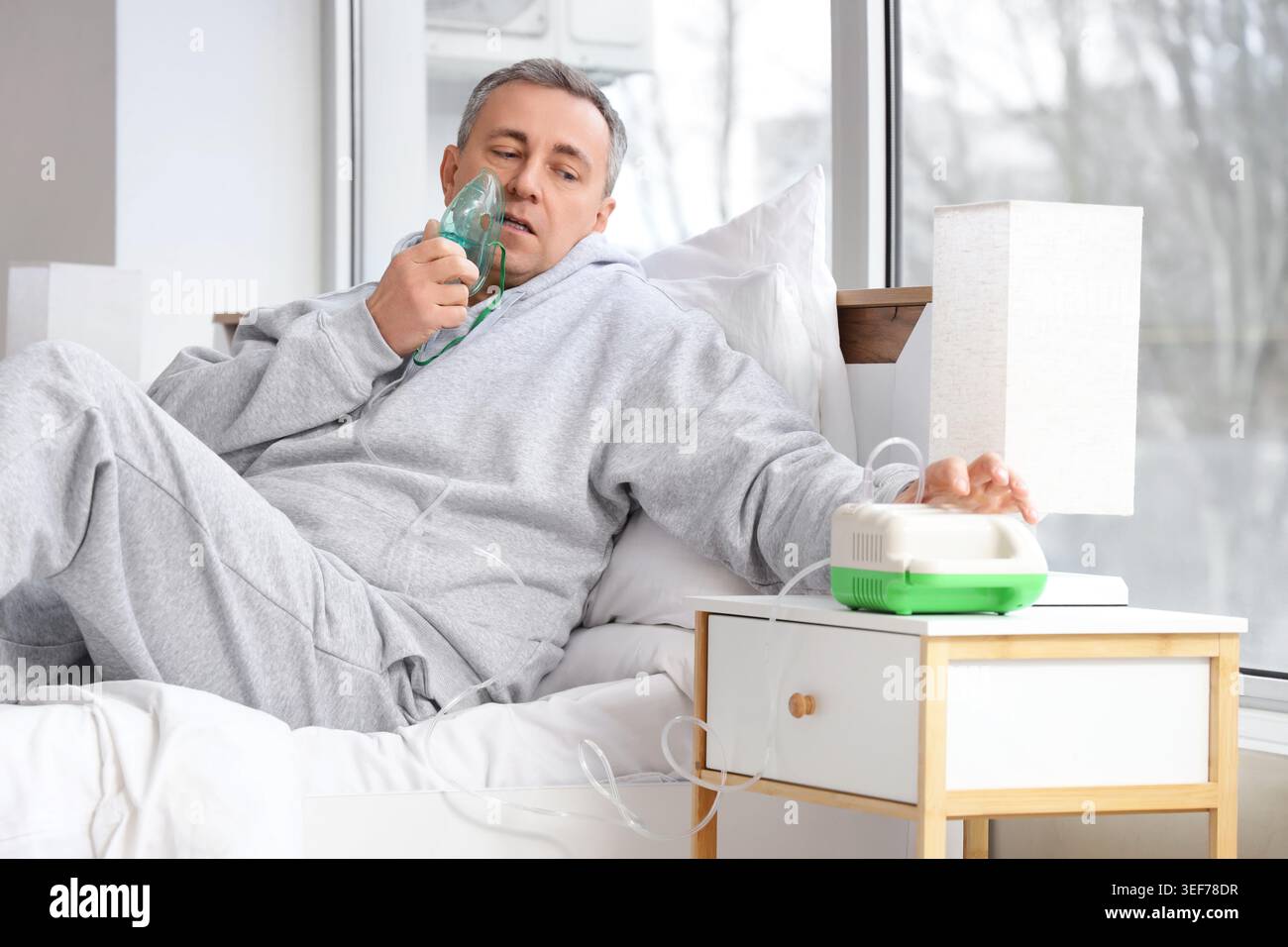 Mature man using nebulizer in bedroom Stock Photo