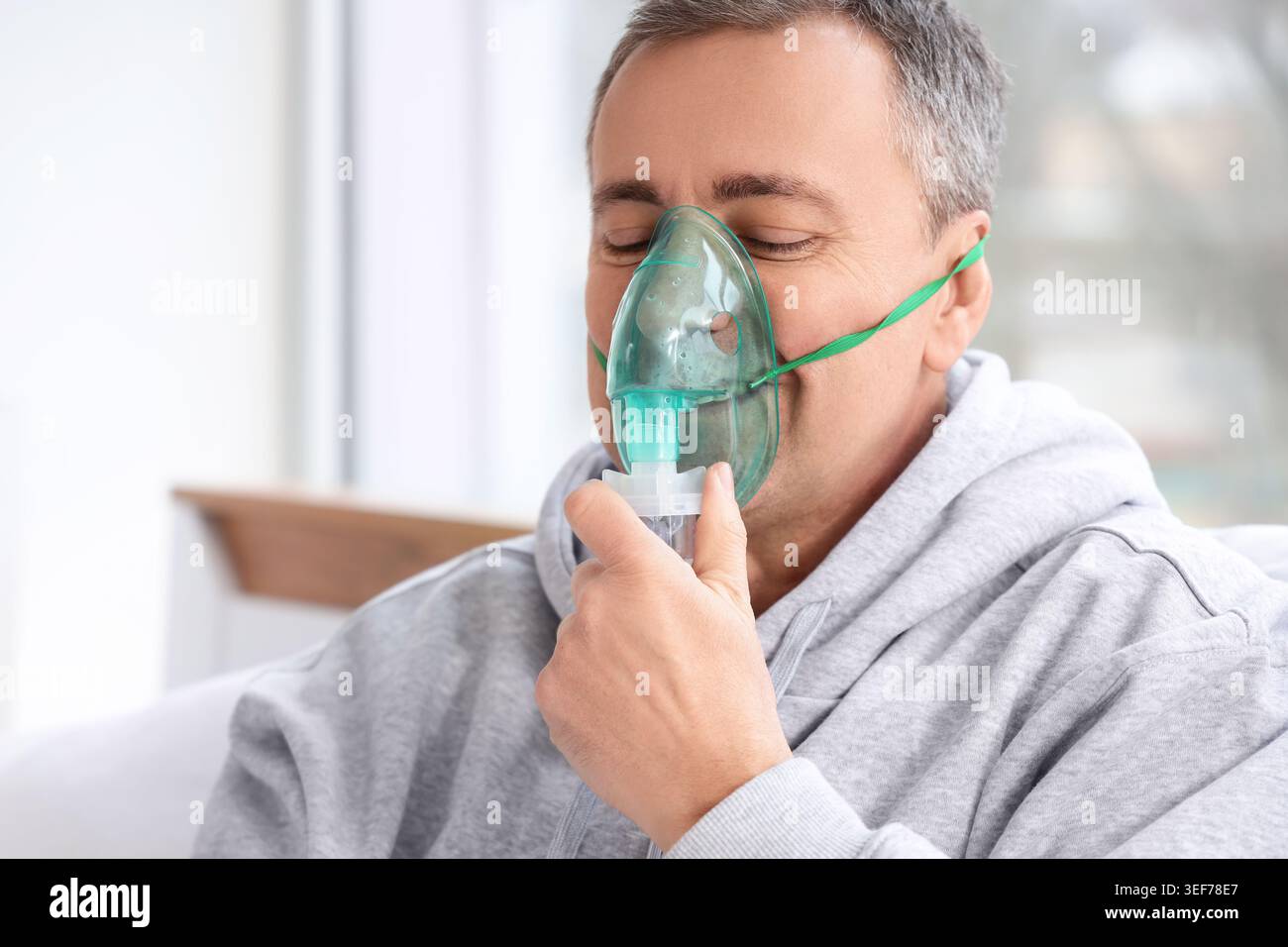Mature man using nebulizer in bedroom, closeup Stock Photo