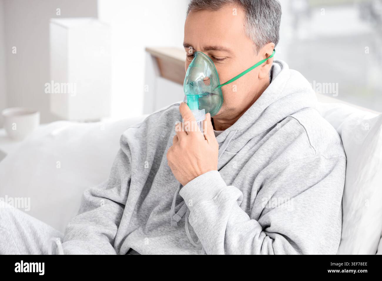 Mature man using nebulizer in bedroom Stock Photo