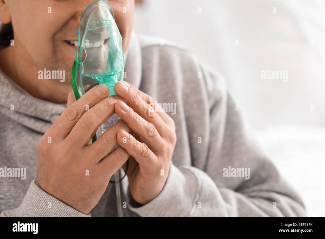 Mature man using nebulizer in bedroom, closeup Stock Photo