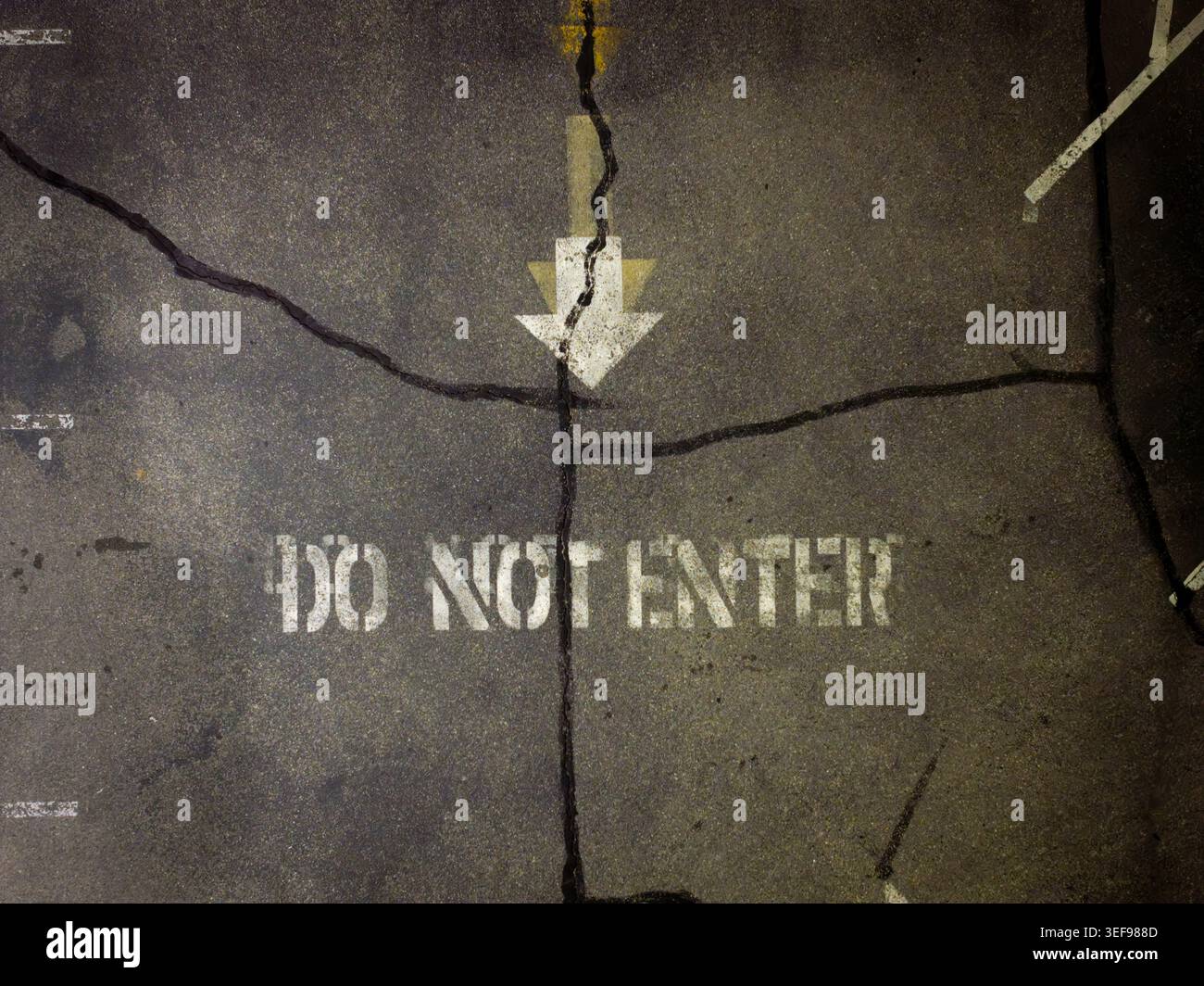 Damaged pavement features spray-painted warning text Stock Photo