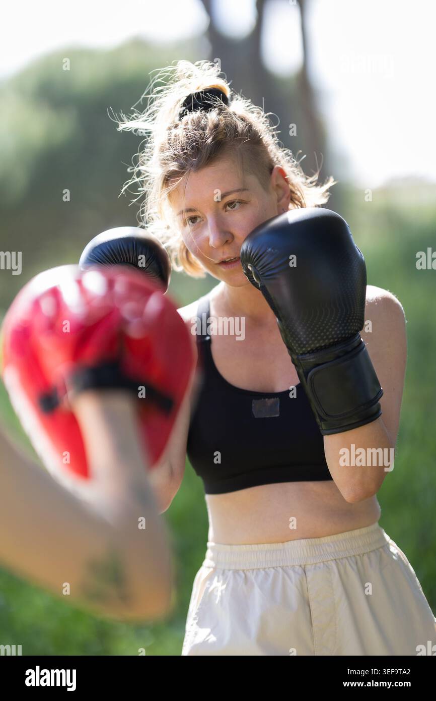 Woman training boxing with punch mitts outdoors Stock Photo
