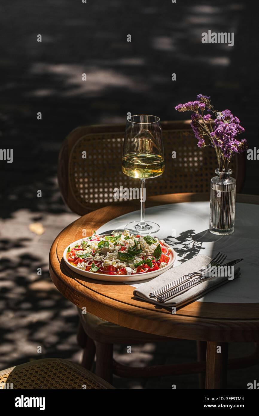 Mediterranean salad with wine on sunny table Stock Photo