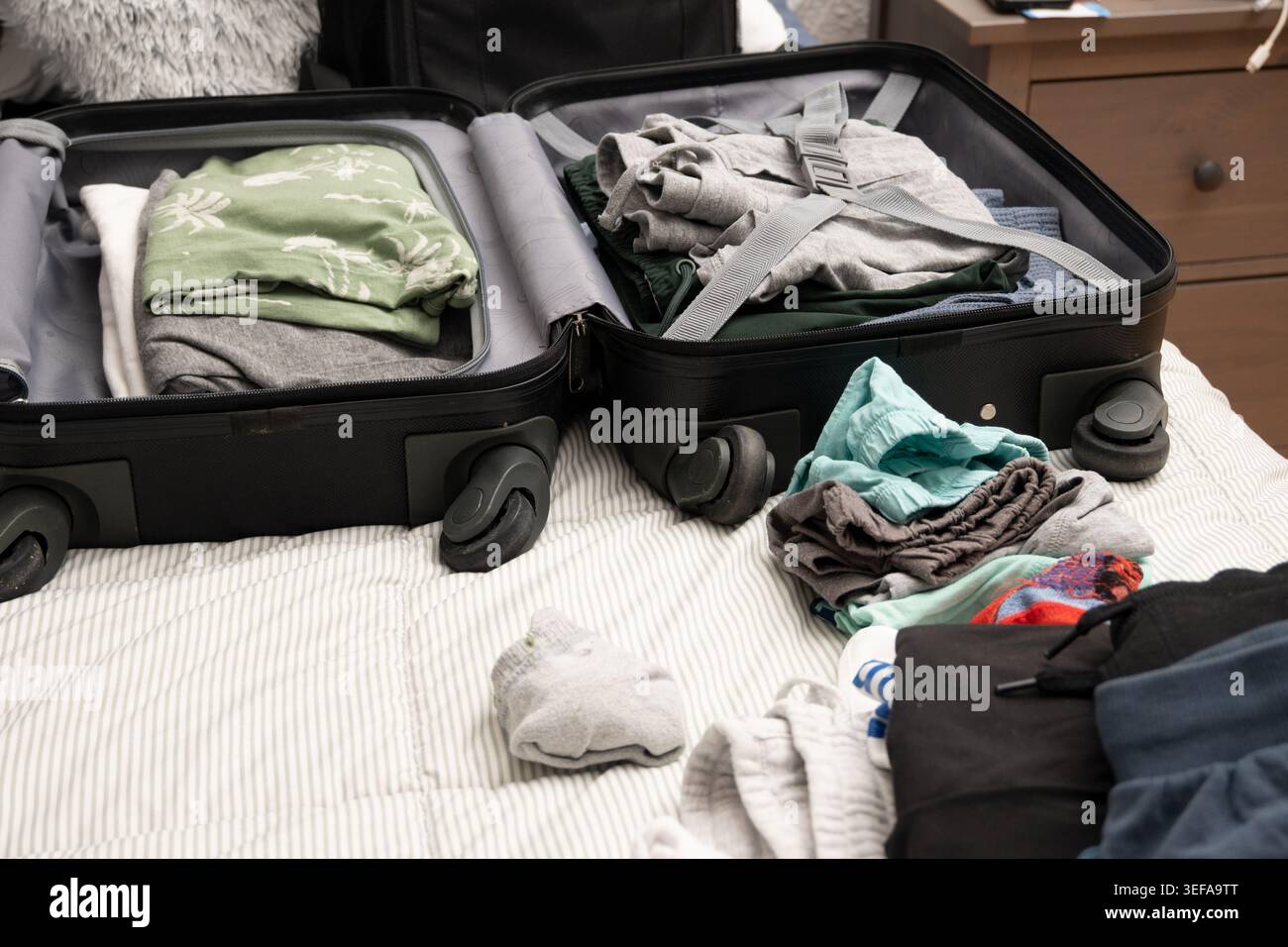 Suitcase on a bed with clothes for preparing a vacation trip Stock Photo