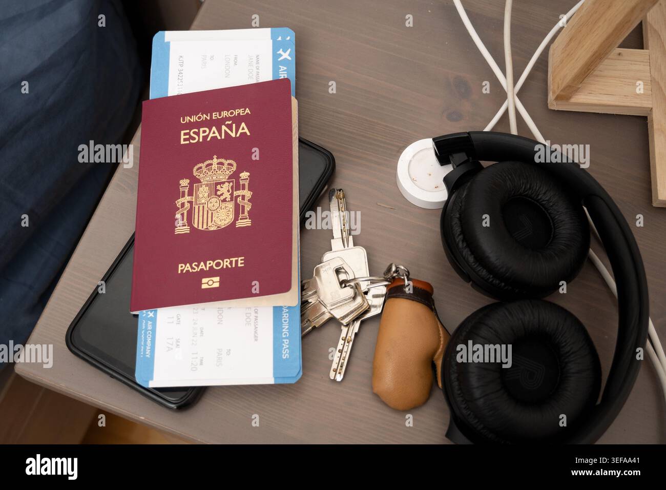 Spain passport, boarding pass, keys, smartphone and headphones on a bedside table Stock Photo