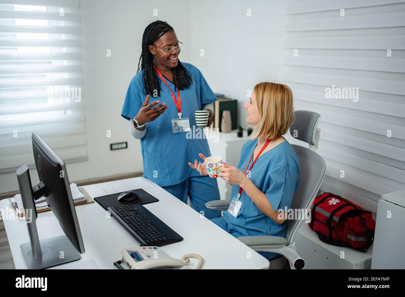 Diverse nurses collaborating and discussing in hospital office during break Stock Photo