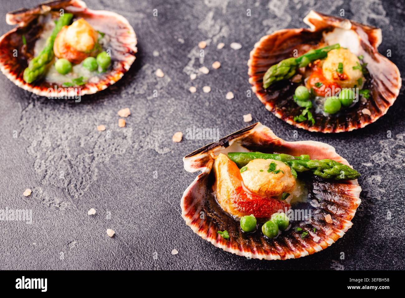 Cooked scallops with vegetables on a dark background Stock Photo