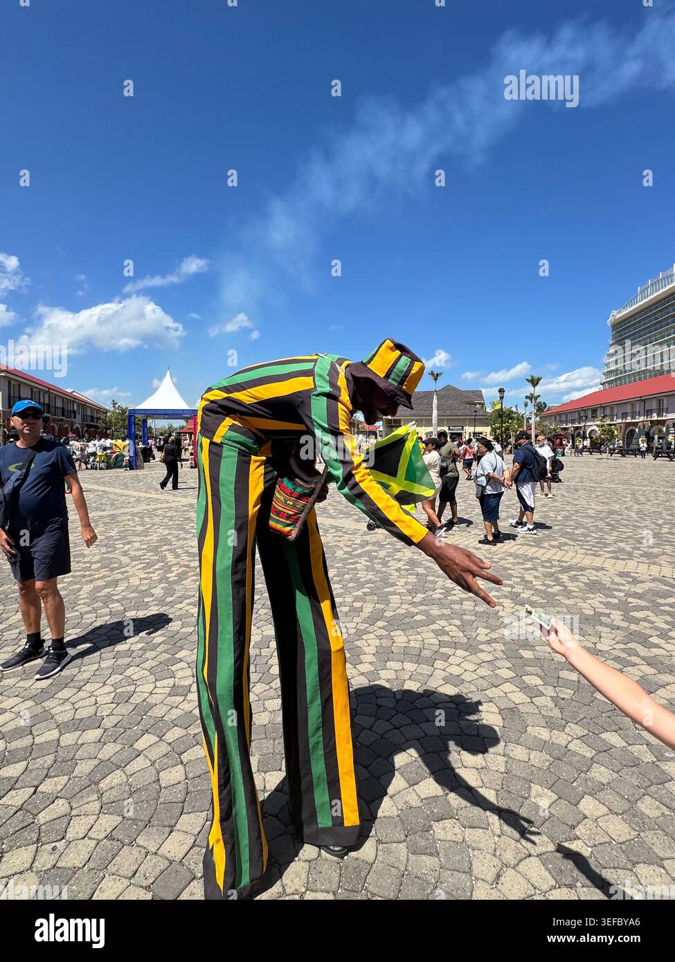 Street artist on high stilts interacting with tourists at the cruise port terminal in - Smartphone Captured Stock Image