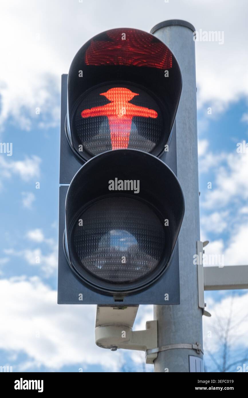 Red pedestrian signal is active at a traffic light indicating a stop ...