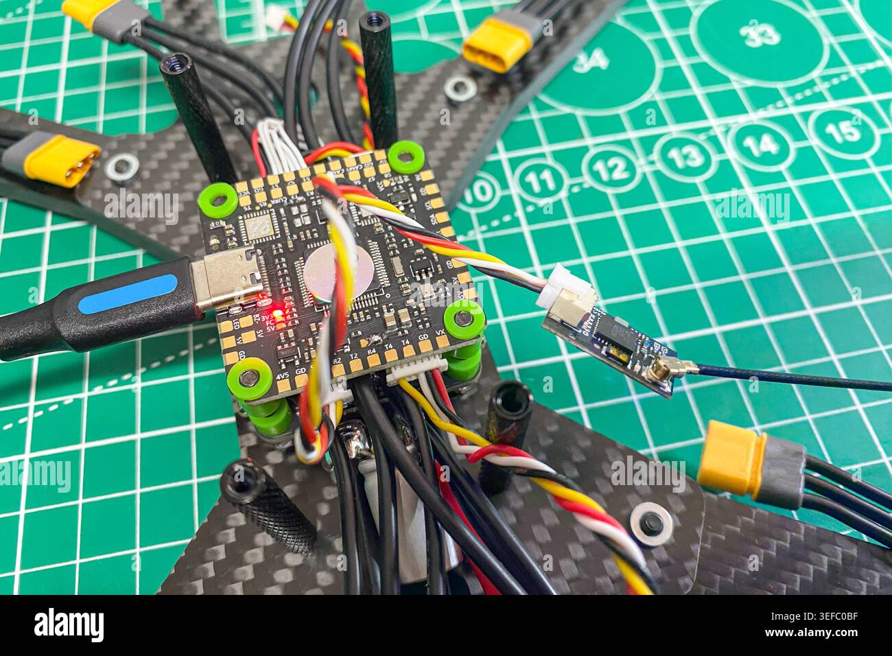 An assembled sport FPV drone body with a stack flight controller and DIY USB-flashed electronic speed controller is ready for flight . Close-up Stock Photo