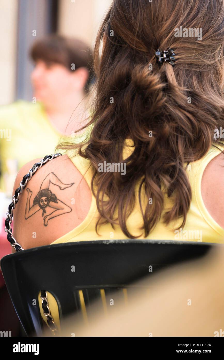 Woman Sicily, rear view of a young Italian woman with a tattoo of the trinacria - the three legged symbol of Sicily - shown on her shoulder, Sicily Stock Photo