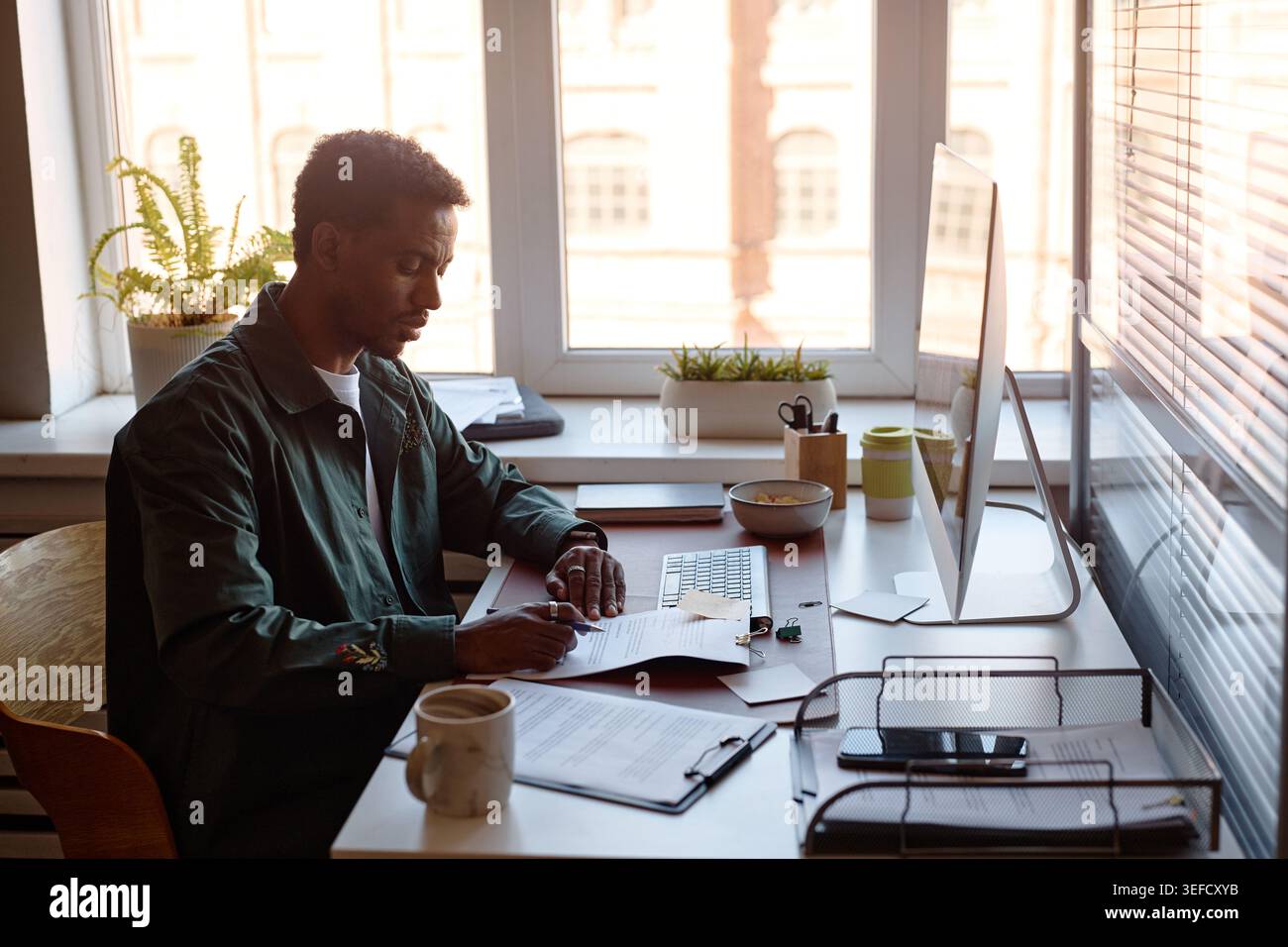 Black Man Reviewing Documents at Desk for Office Administration Stock Photo