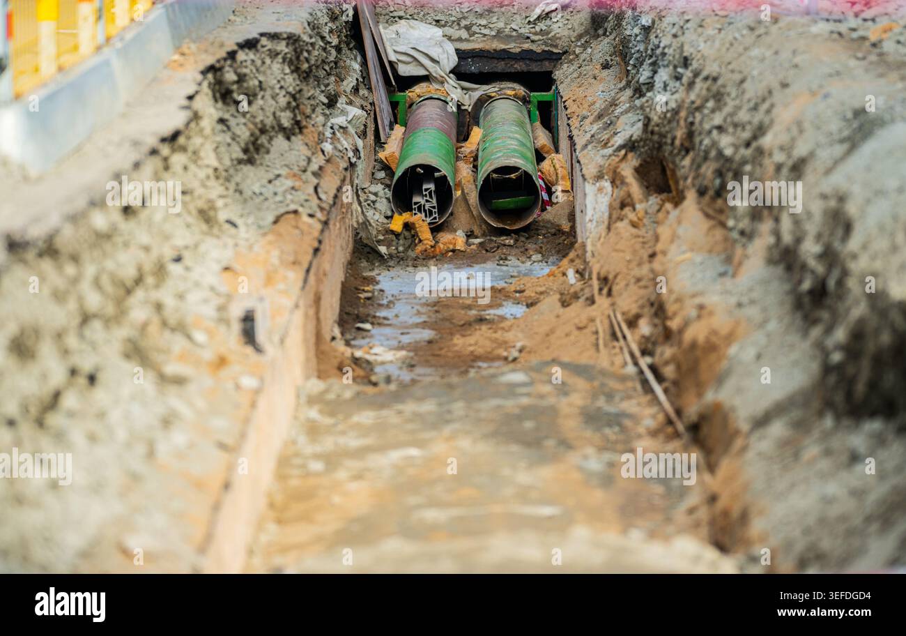 Underground construction trench with exposed pipes Stock Photo - Alamy
