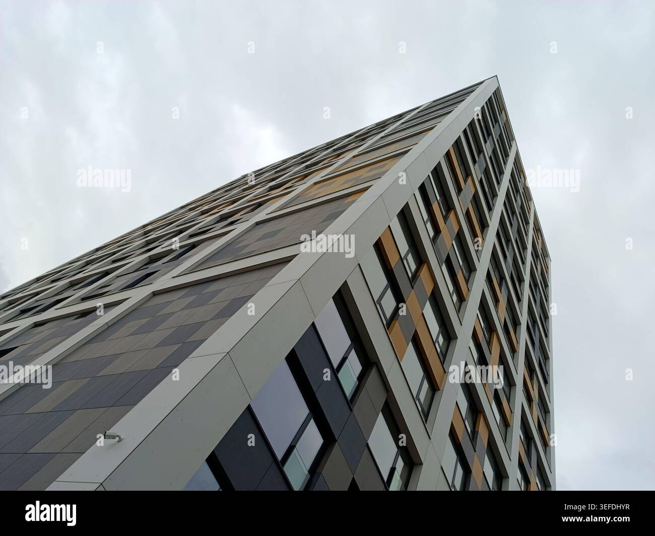 Modern residential tower featuring a striking pattern of square and rectangle windows and panels, creating a dynamic, geometric facade under an overca Stock Photo