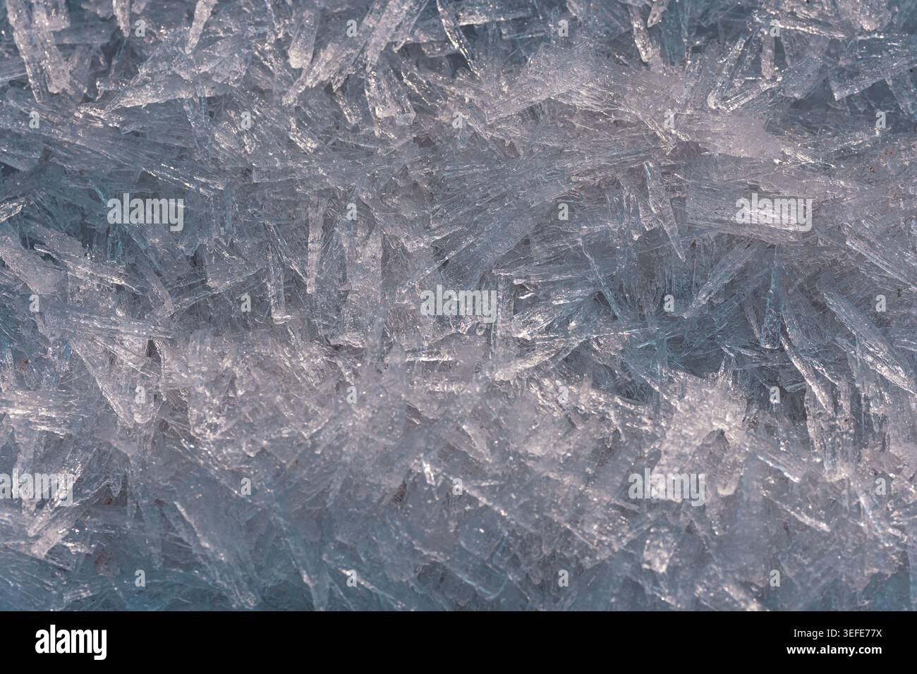Sharp transparent ice crystal formations creating intricate geometric patterns in a detailed close‑up view Stock Photo