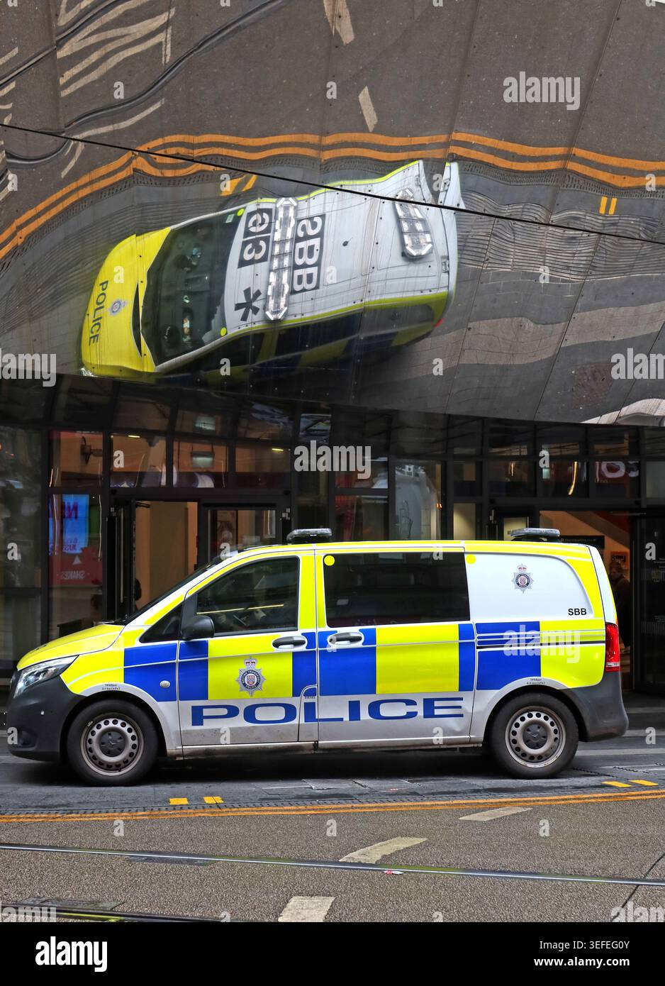 West Midlands Police car reflected in the glass frontage of Birmingham New Street station, England, UK. Stock Photo