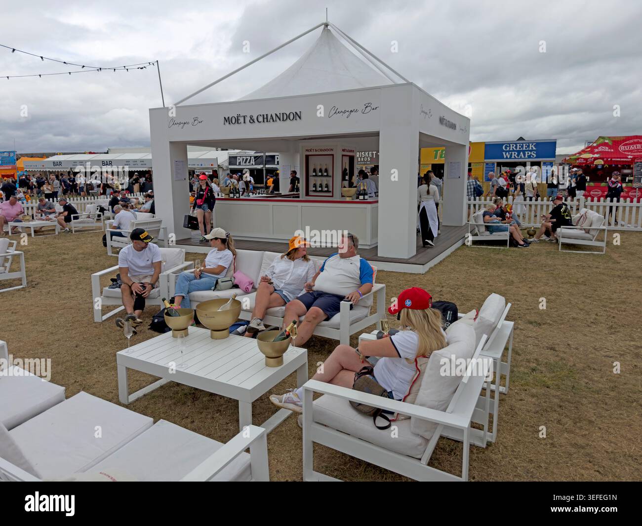 Silverstone Grand Prix spectators relax at a Moët & Chandon champagne bar, part of the premium F1 hospitality scene. Stock Photo