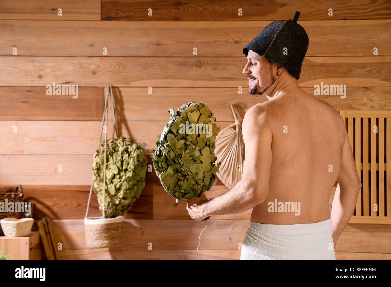 Handsome man with whisk in sauna, back view Stock Photo
