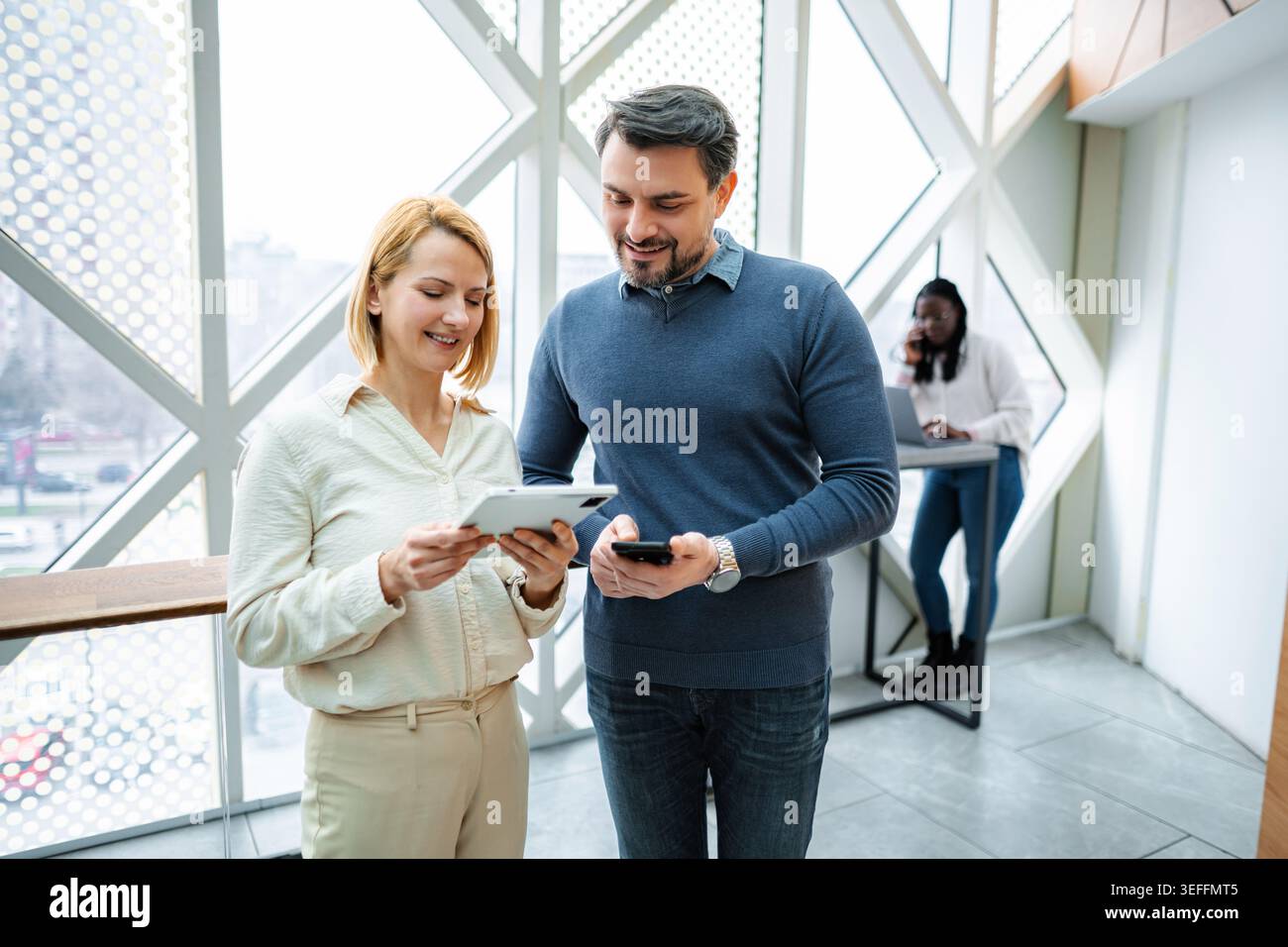 Coworkers collaborating on digital tablet in modern office Stock Photo