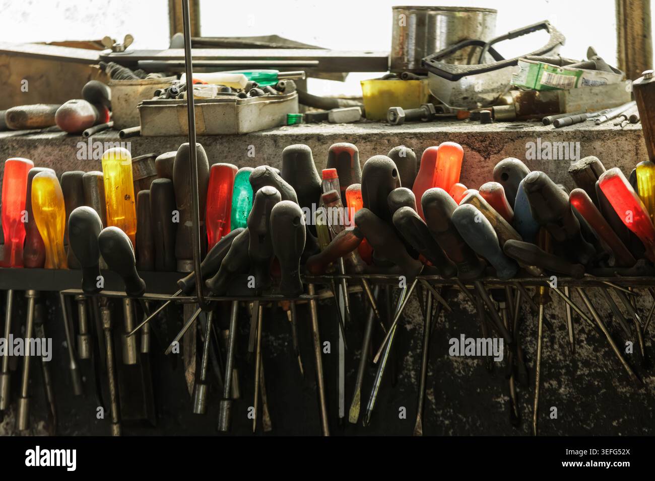 Close-up of various screwdrivers and hand tools stored on a workbench in an industrial workshop, showing organized chaos, craftsmanship and real worki Stock Photo