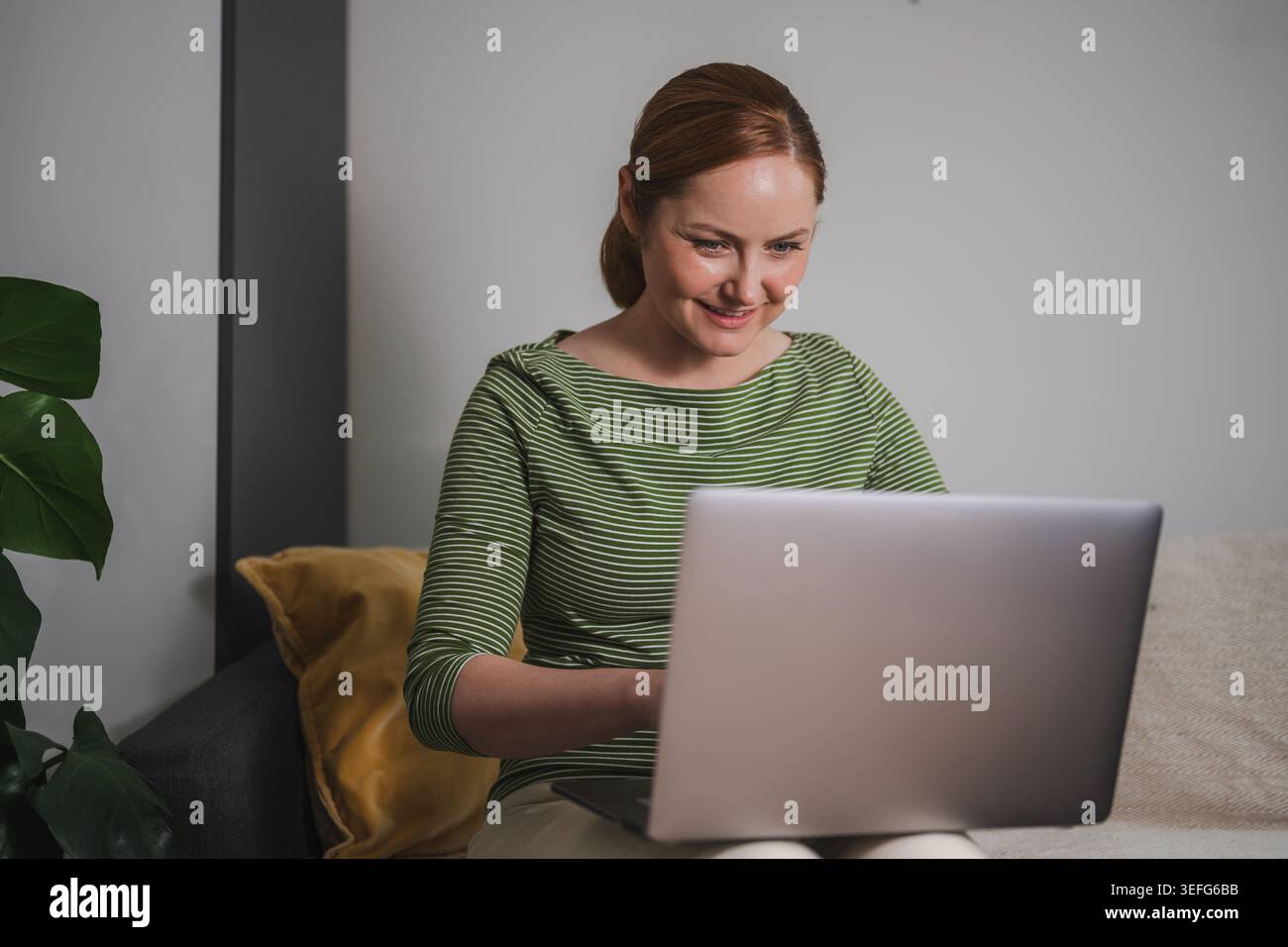 Comfortable remote work concept, woman using laptop from home Stock Photo