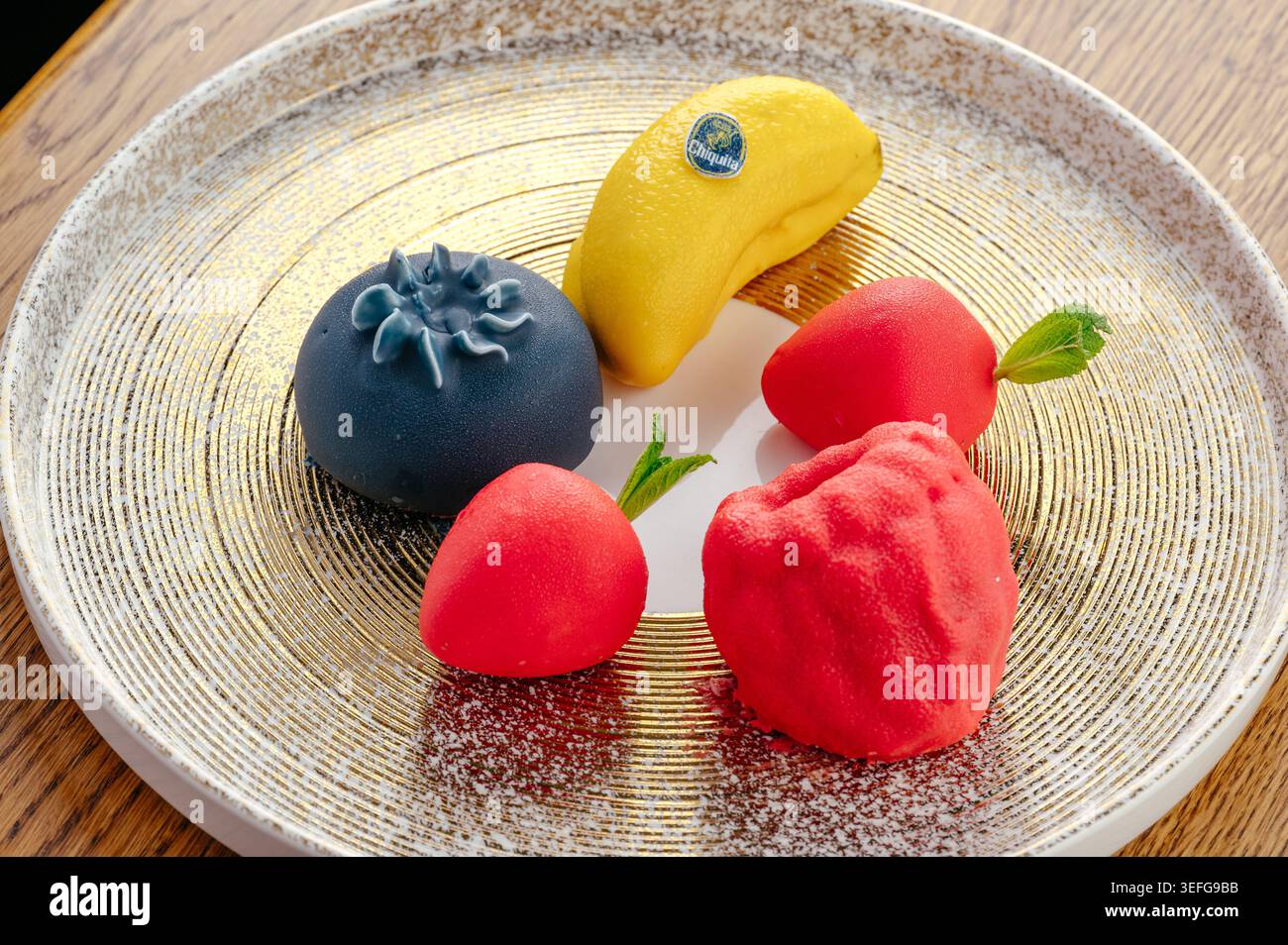 Assorted gourmet fruit shaped cakes on a gold platter Stock Photo