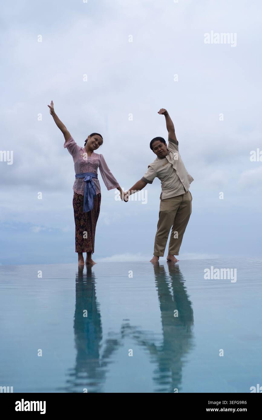 oyful Balinese couple making heart shape at infinity pool, Bali Stock Photo