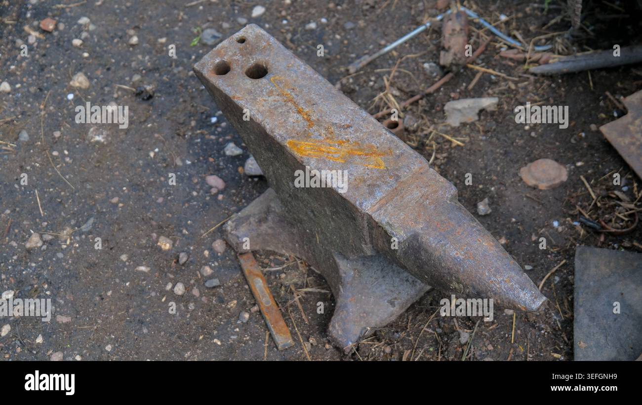 Old Rusty Blacksmith Anvil with Hammer in Workshop Stock Photo