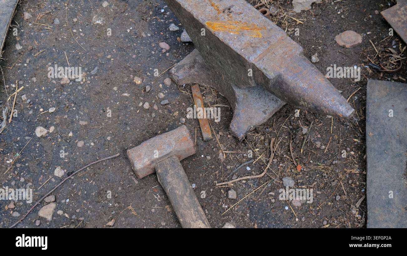 Old Rusty Blacksmith Anvil with Hammer in Workshop Stock Photo