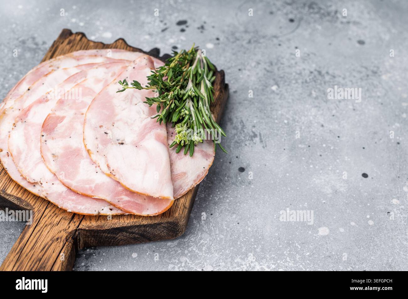 Traditional deli meat (Pancetta) and serving fork on a minimal grey background, perfect for a clean menu design Stock Photo