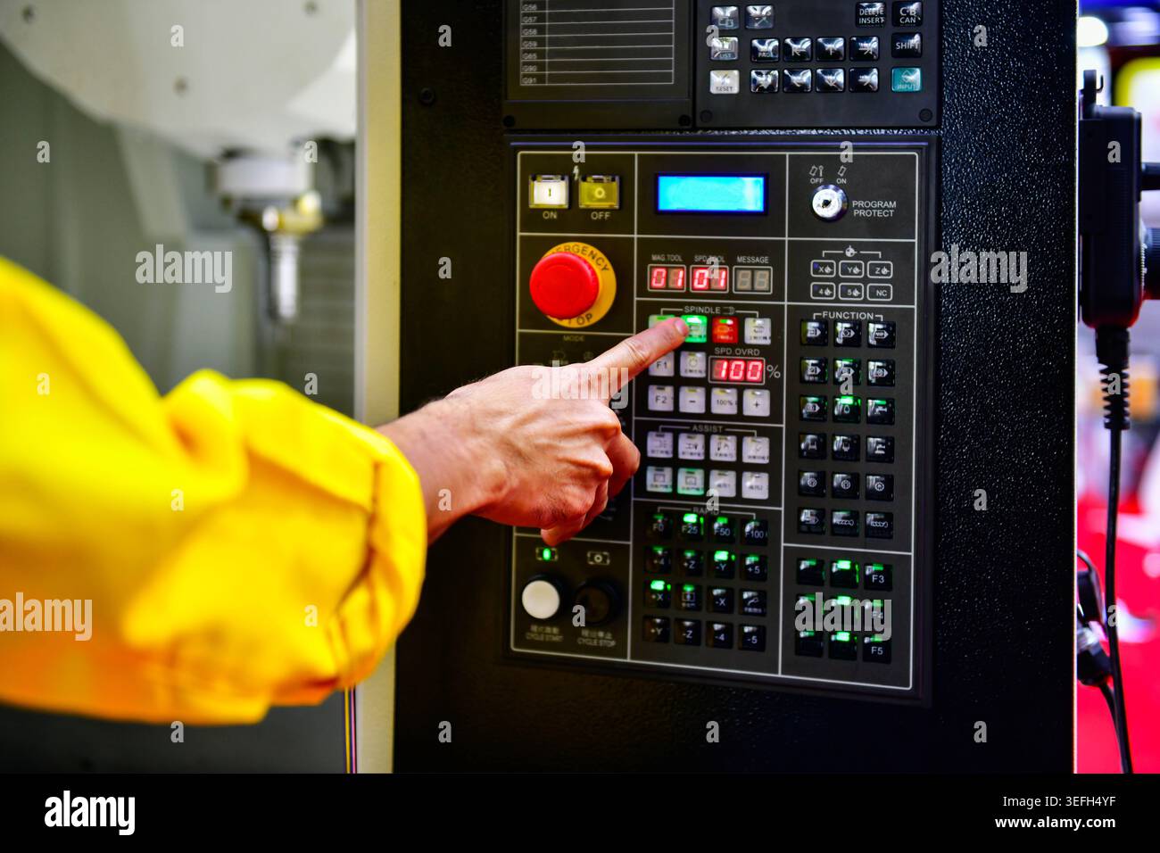 Operator hand pressing button on CNC machine control panel, industrial manufacturing process Stock Photo