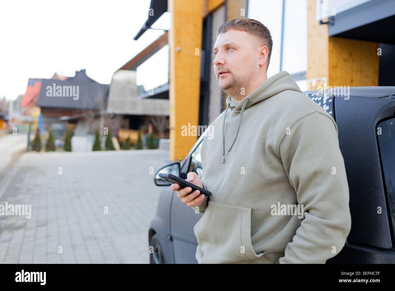 Man using smartphone standing near car outdoors Stock Photo