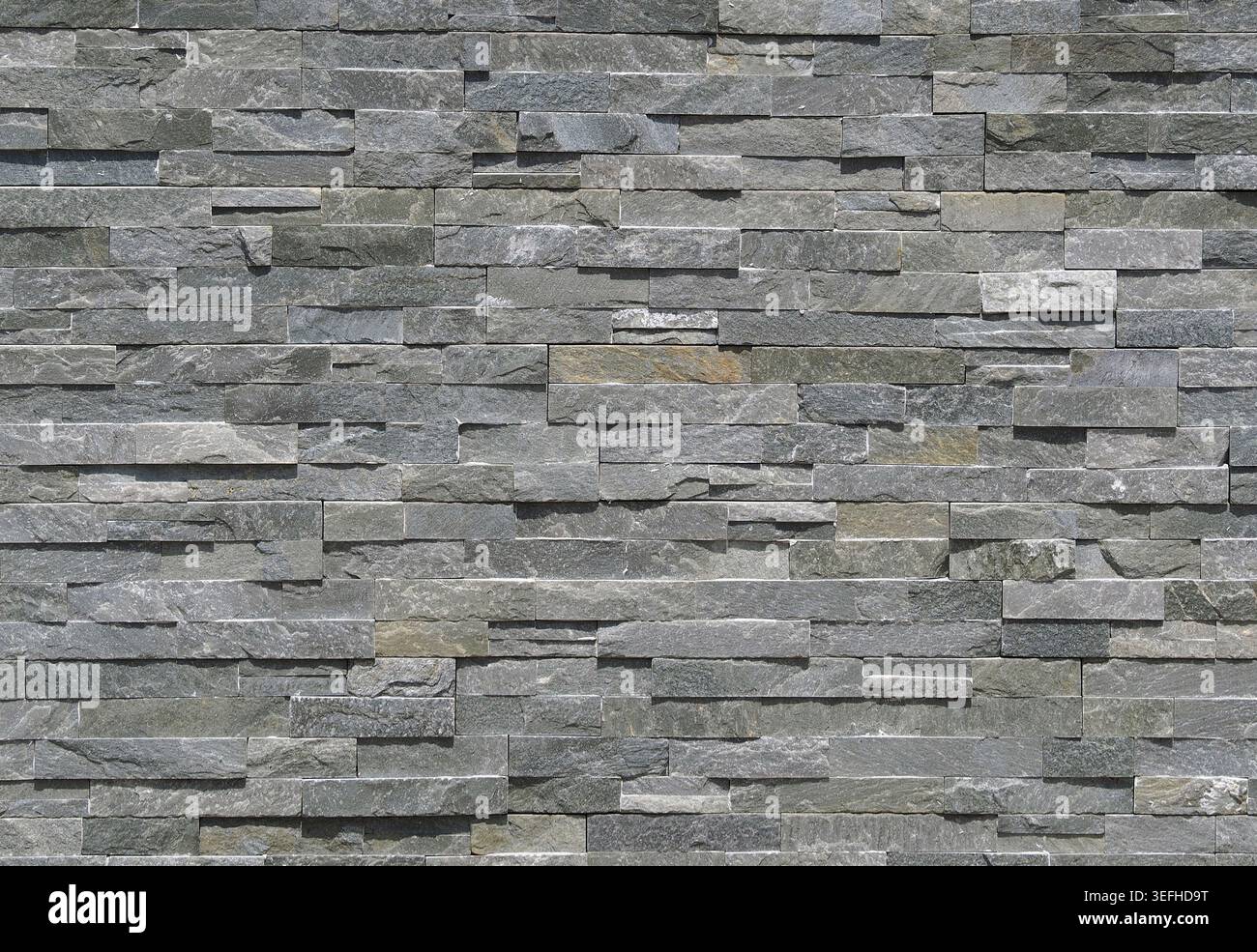 Stone wall cladding made of gray shades strips of rock . Background and texture Stock Photo