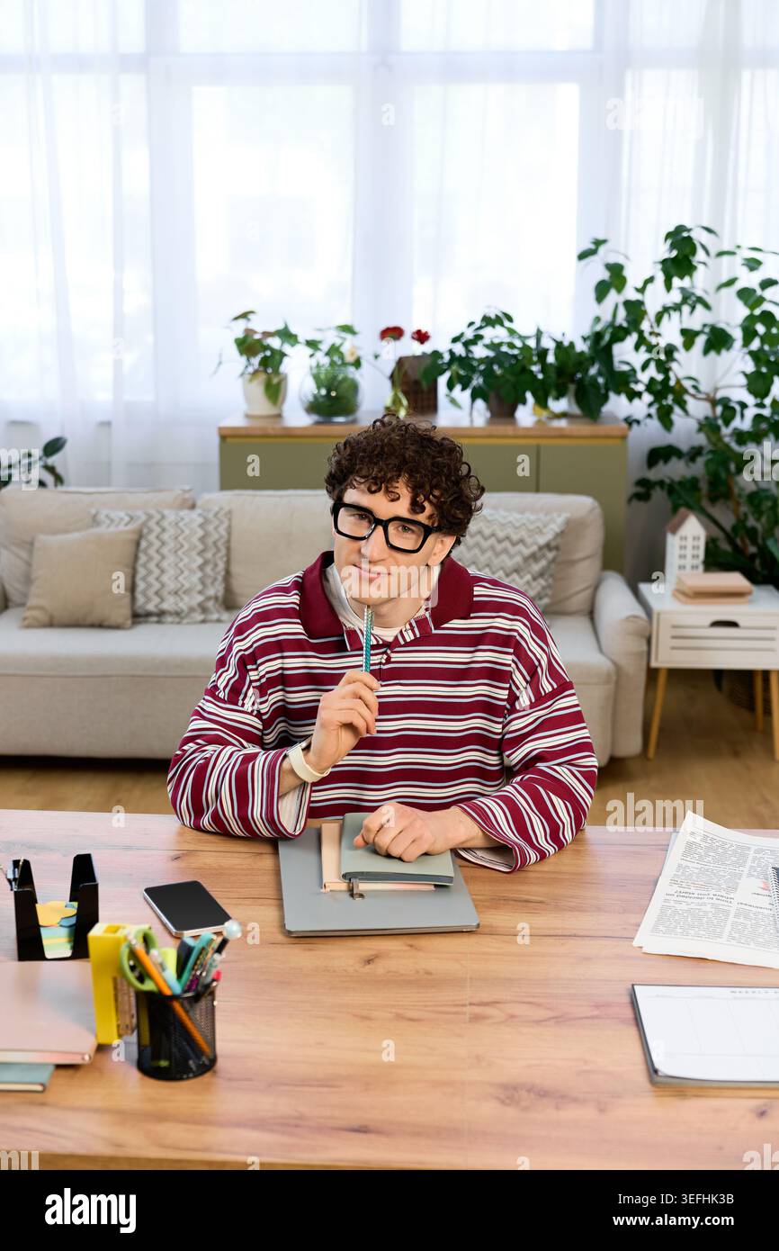 Young man with curly hair relaxes in his stylish apartment while brainstorming ideas. Stock Photo