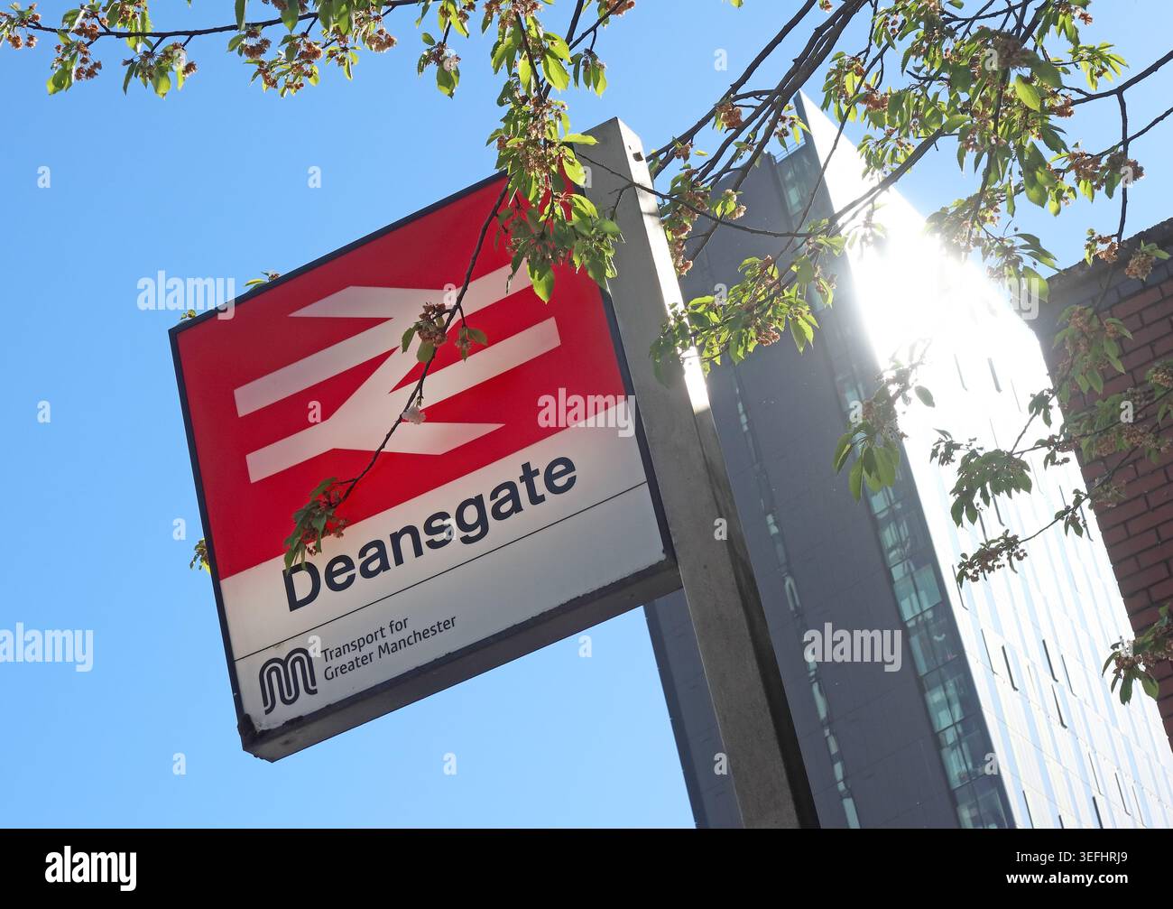Bright spring sunshine behind the Deansgate railway station sign beside new Manchester city centre tower blocks Stock Photo