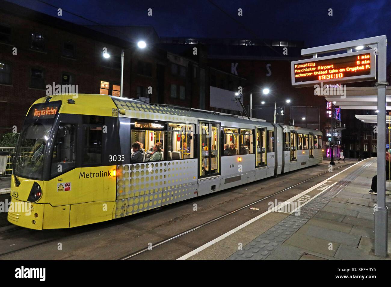 Manchester yellow Metrolink tram bound for Bury waits at Shudehill tram stop under evening lights in the city centre Stock Photo