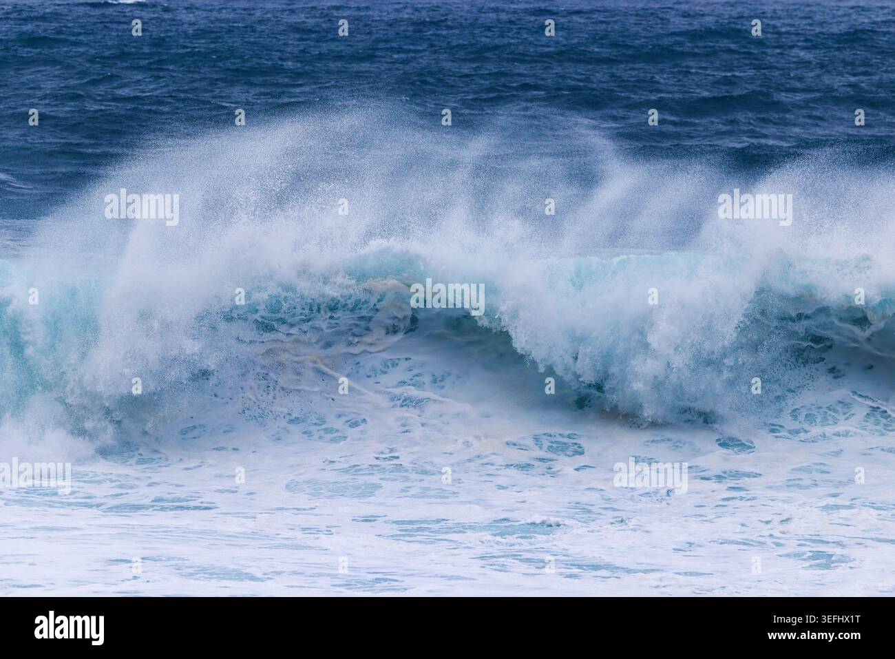 Powerful Turquoise Wave Breaking in the Deep Blue Ocean Stock Photo