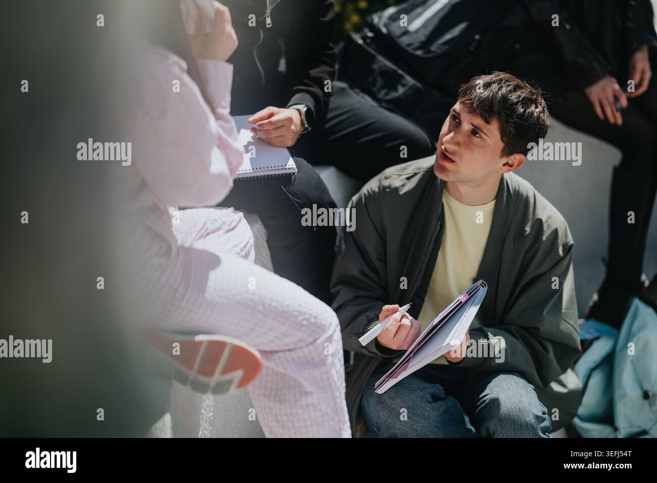 High school students studying and discussing notes outdoors during a group study session Stock Photo