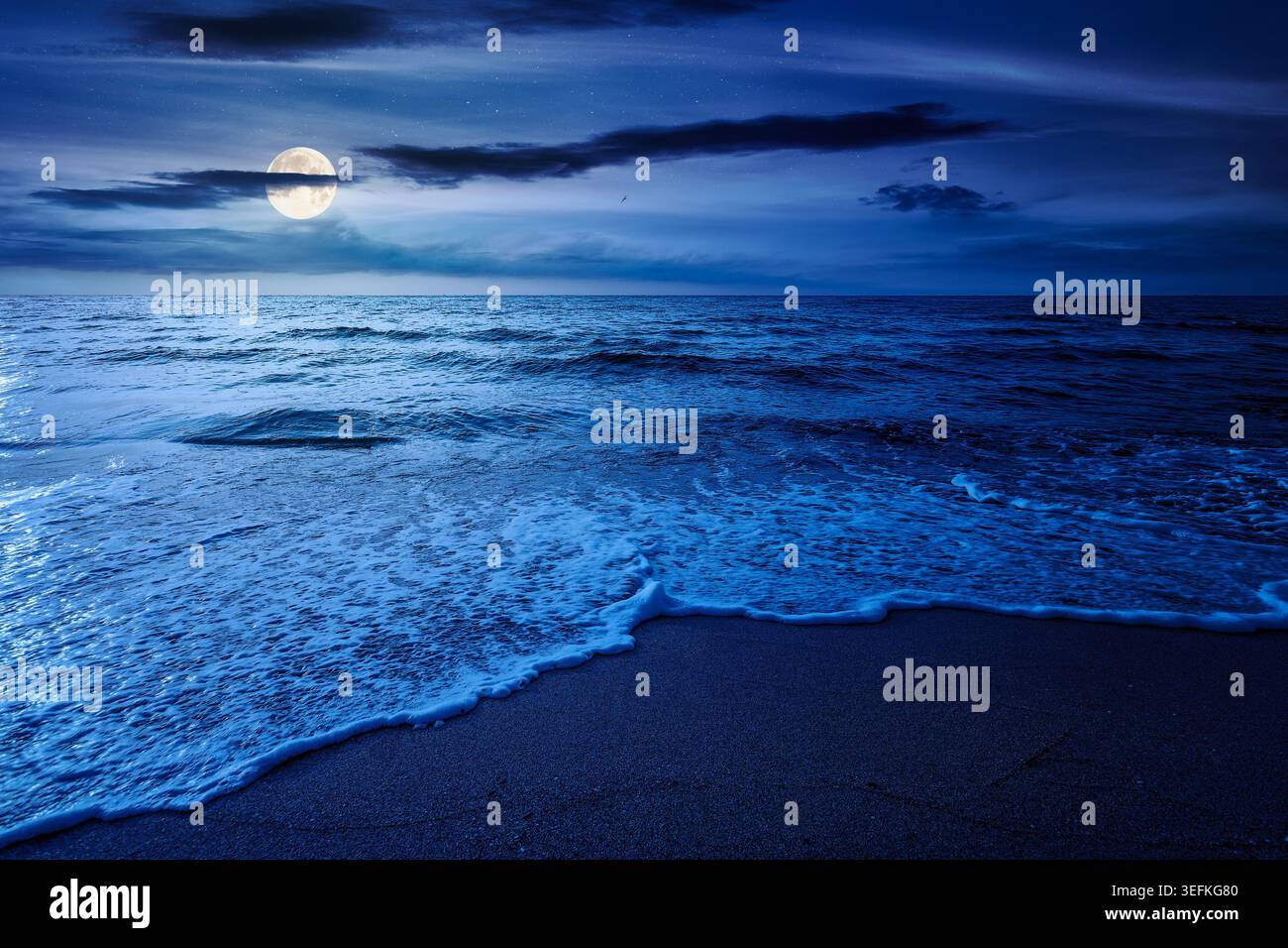 autumn vacation at the sea at night. full moon over beautiful seascape. calm waves wash the sandy beach. image with cloudy sky above horizon. mysterio Stock Photo