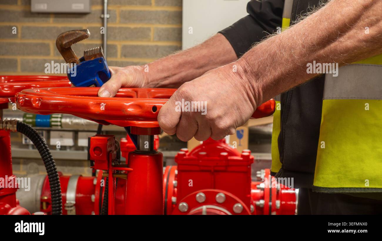 Sprinkler system service engineer operating a red flow valve with a ...