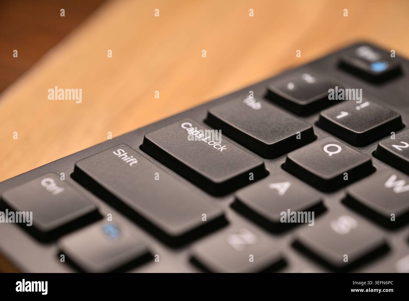 Side Angled Top View Macro Close-Up Black Computer Keyboard Highlighting Caps Lock Key on Blurred Tech Backgrounds Stock Photo