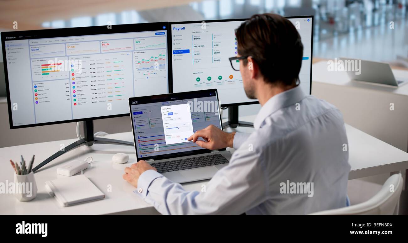 Mature Business Manager Reviews OKR Dashboard On Laptop Tracking Workforce Progress And Performance. Stock Photo