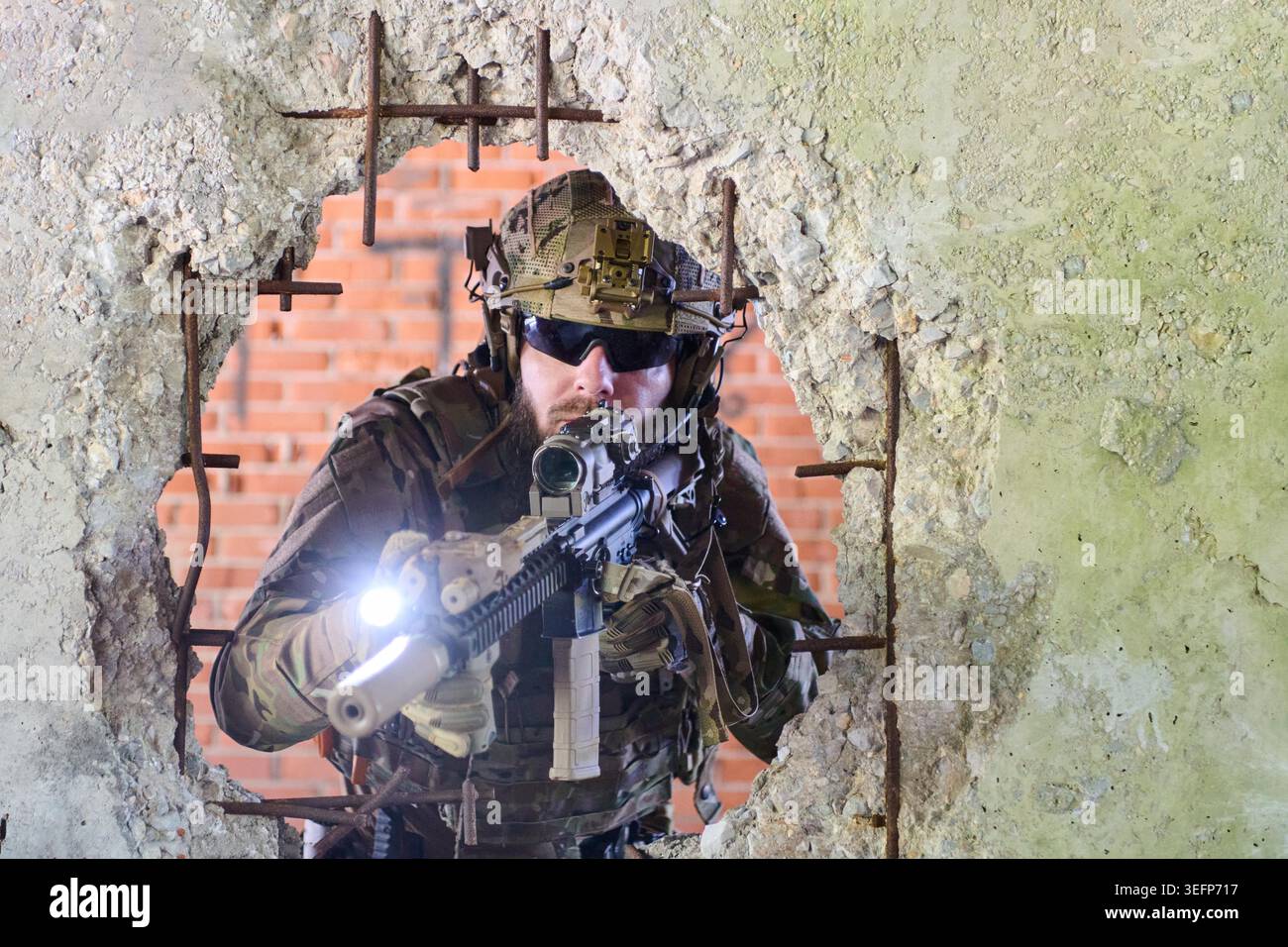 Armed tactical soldier in camouflage and helmet aims a rifle with ...