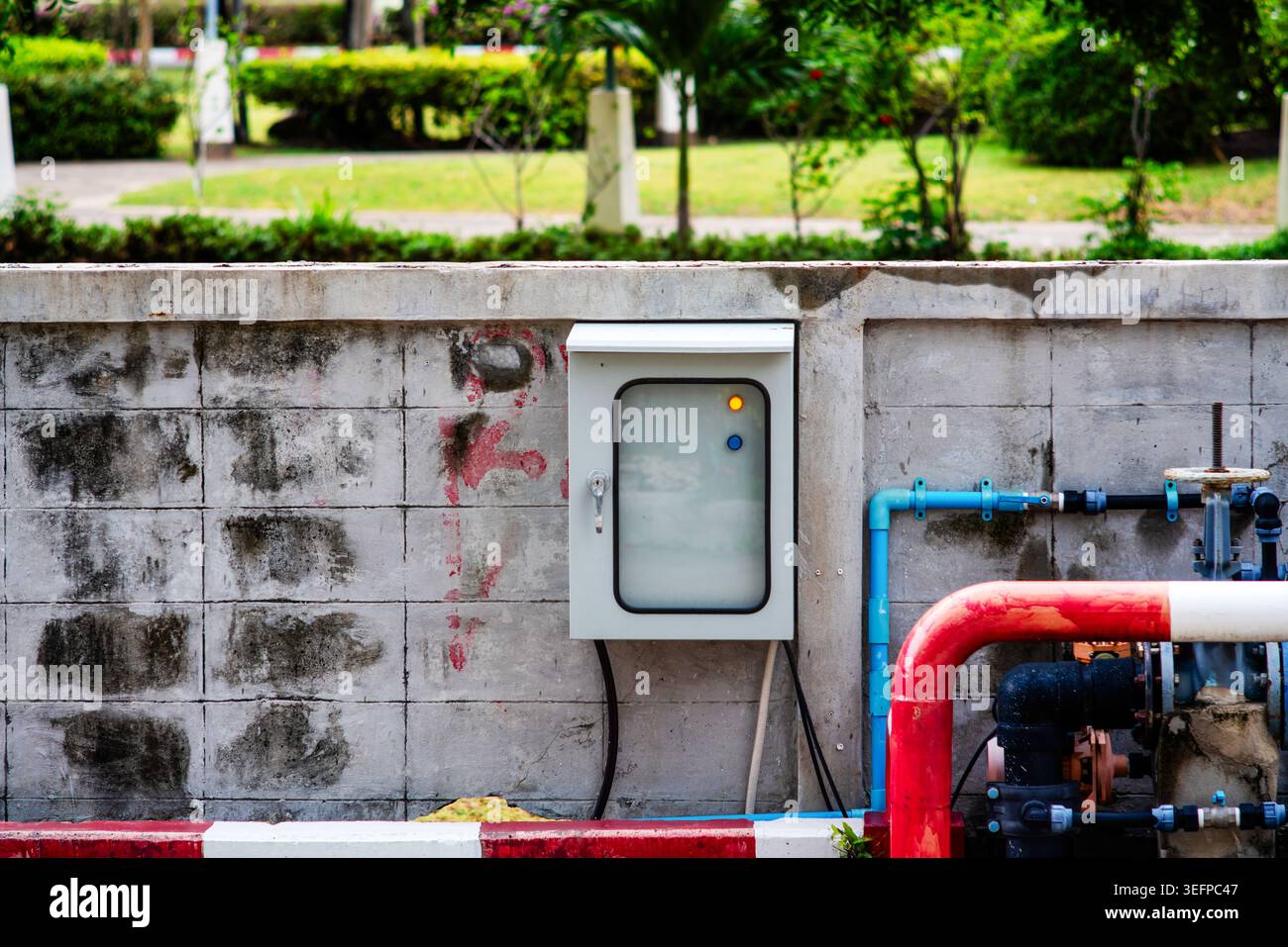 This image displays a utility box attached to a concrete wall with ...