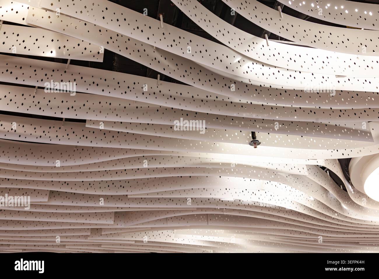Modern abstract white wave ceiling panel design with perforated dots pattern texture close up Stock Photo