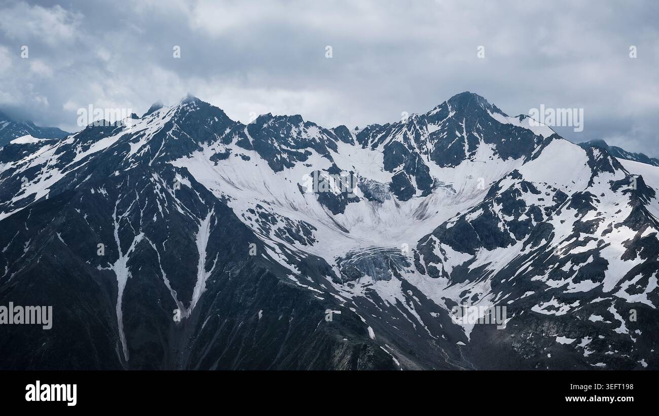 Snow Covered Mountain Range Under Cloudy Sky Stock Photo