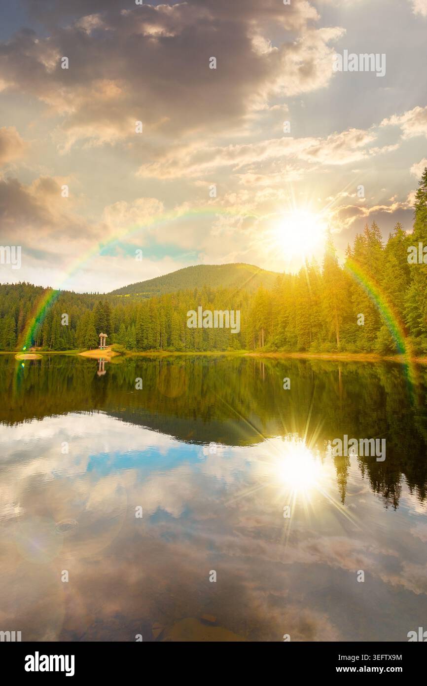 sunset over landscape by the lake. coniferous forest near the lake and the forest mountain. awesome summer view of carpathian mountain reflection on s Stock Photo
