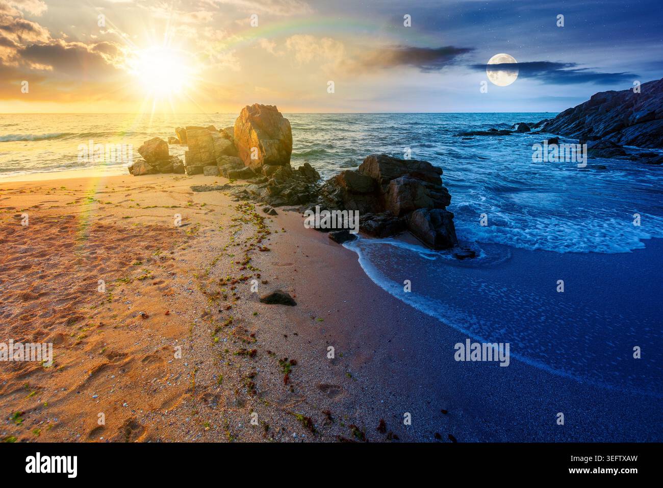 huge stones on the sandy beach. day meet night. wonderful holiday season background at the sea at twilight. sun and moon over clouds on the epic sky a Stock Photo